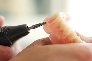 close up of someone finishing off a custom set of dentures