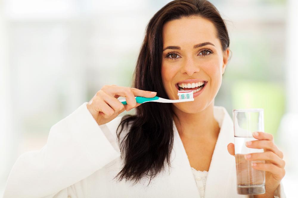 woman brushing after getting her teeth whitened in dunedin