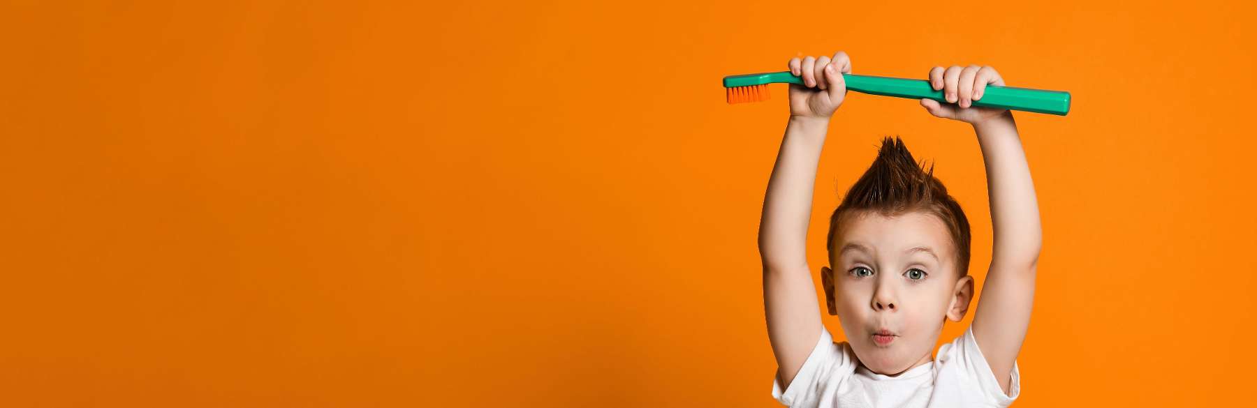 Young boy holding up large tooth brush at family dentist in Dunedin, Otago