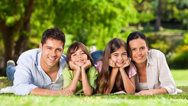 mom, dad, son, and daughter smiling in the park