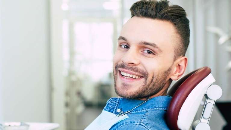 man smiling in dental chair after getting a filling in dunedin