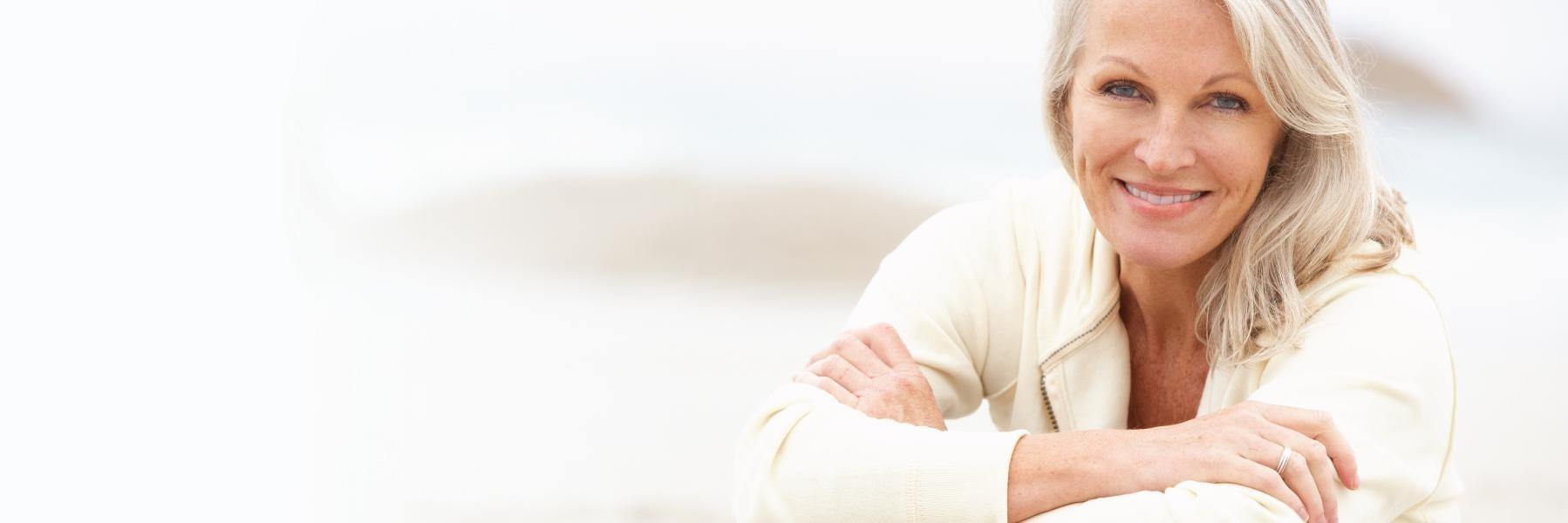 Woman with dental implants in Dunedin smiling on the beach