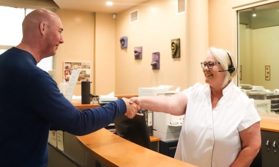  dentist Dunedin | Receptionist shaking hands with patient